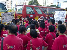 观光客们被催促着上车前，仍把握机会不停地看着法轮功学员举着的真相展板