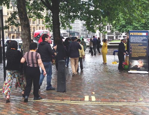 图3：中国大陆来的旅游团经过法轮功学员活动场地，有人在拍照摄像，有人在悄悄观察