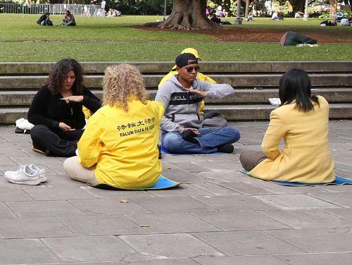 '图 3：两位来自墨西哥的游客认真的学炼法轮功第五套功法'