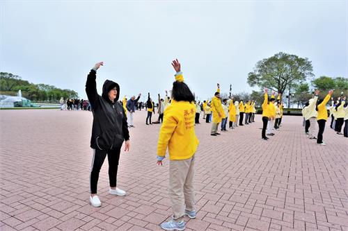 '图8：来自明尼阿波利斯的Julie则当场跟法轮功学员学起了炼功动作。'