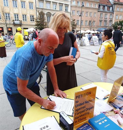 '图16：购买《转法轮》的波兰夫妇在请愿书上签名，反对中共迫害法轮功'